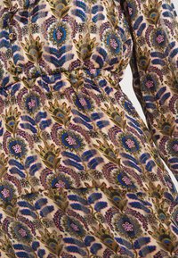 Robe à manches longues avec taille élastique, présentant un motif floral en bleu, rose, vert olive et marron sur fond beige.