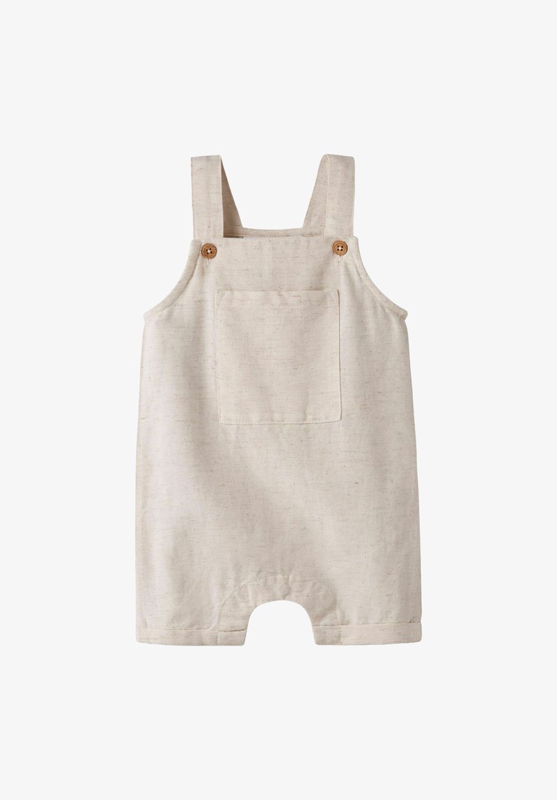 Barboteuse beige pour tout-petit avec poche avant, bretelles à boutons aux épaules et ourlets des jambes retroussés, fabriquée en tissu texturé.