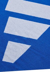 Asciugamano blu con una superficie testurizzata che mostra tre grandi triangoli geometrici bianchi in un motivo, in contrasto con il colore di sfondo.