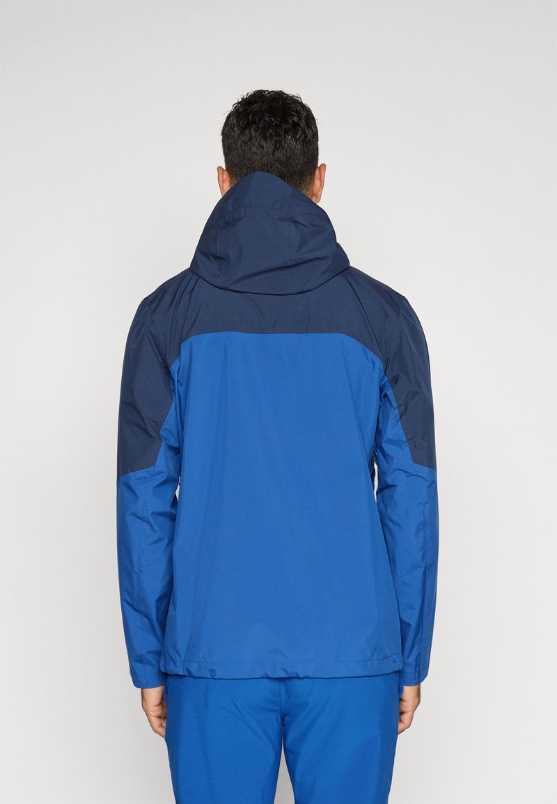 Niebieska kurtka z kontrastującą granatową górną częścią, z kapturem, gładką teksturą i elastycznymi mankietami. Widok z tyłu ukazuje minimalne detale.