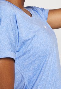 Ljusblå, kortärmad, v-ringad träningsskjorta i texturerad tyg, med en subtil logo på bröstet och sömlös design.