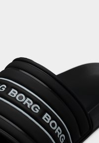 Μαύρο σανδάλι με φάσες με επένδυση, με ανάγλυφο λευκό κείμενο "BORG" και λεπτομέρειες με γαλάζιο περίγραμμα.