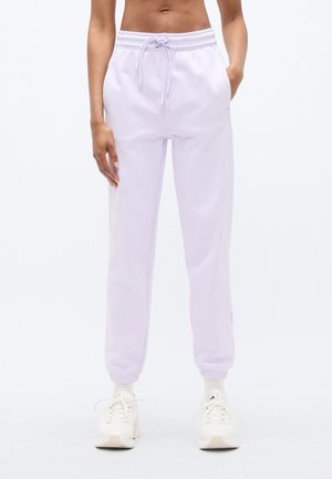 Lilla joggingbukser lavet af blødt stof med elastik i taljen og snøre, manchetter ved anklerne og sidelommer. Synligt logodetalje.