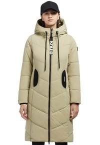 Pūšīgs gaiši brūns mētelis ar rāvējslēdzēju priekšā, regulējamu kapuci un melniem akcentiem. Iezīmējas ar izšūtu rakstu un sānu kabatām, izgatavots no sintētiska materiāla.