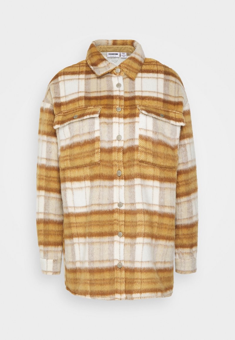 Flanellipaita keltaisessa, ruskeassa ja valkoisessa ruutukuosissa. Sisältää kauluksen, napittoman etuosan ja kaksi rintataskua, joissa on napsulukot.