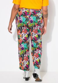 Kleurige pantalons met verschillende motieven, waaronder maskers en bladeren, gemaakt van een luchtige stof, met een elastische tailleband en een relaxte pasvorm.