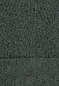 Ciemnozielona dzianinowa czapka z teksturowanym wzorem, z podwiniętym mankietem i małym logo naszytym z przodu. Miękki materiał z wełny.
