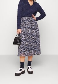 Navy cable-knit sweater paired with a knee-length skirt featuring a floral pattern in blue and white, complemented by black platform shoes.