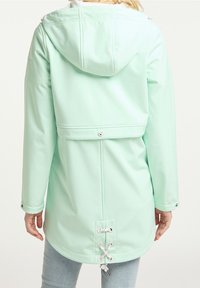 Veste imperméable vert menthe avec capuche, accents de cordon de serrage dans le dos et boutons-pression argentés. Texture lisse et design décontracté.