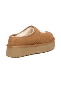 Brown slip-on shoe with fluffy lining, soft suede-like upper, platform sole, and subtle stitching detail. Rounded shape, textured bottom for grip.