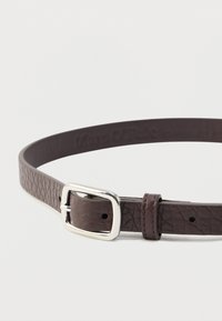 Brązowy, teksturowany skórzany pasek z srebrną, prostokątną klamrą, o smukłym designie i otworami do regulacji na pasku.