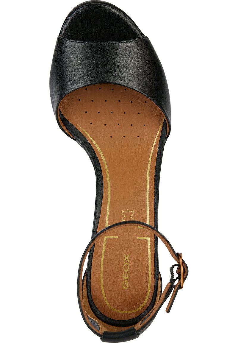 Scarpa con tacco alto, aperta davanti, di colore nero, con tomaia in pelle lucida, soletta imbottita marrone con perforazioni e una sottile cinturino alla caviglia con fibbia.