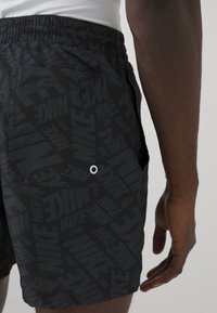 Pantaloni scurți negri cu un design texturat ce prezintă logo-uri Nike repetate. Au o pocketă posterioră cu o grometă pentru drenaj. Talie elastică.
