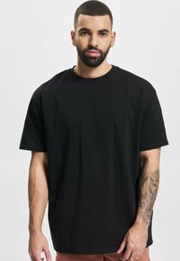 Black cotton t-shirt with a relaxed fit, short sleeves, and a crew neckline. Plain design with no visible patterns or accents.
