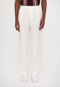 Pantaloni albi cu talie elastică, cu șnur, croi drept, textură moale și design fără cusături. Purtați cu adidași albi.