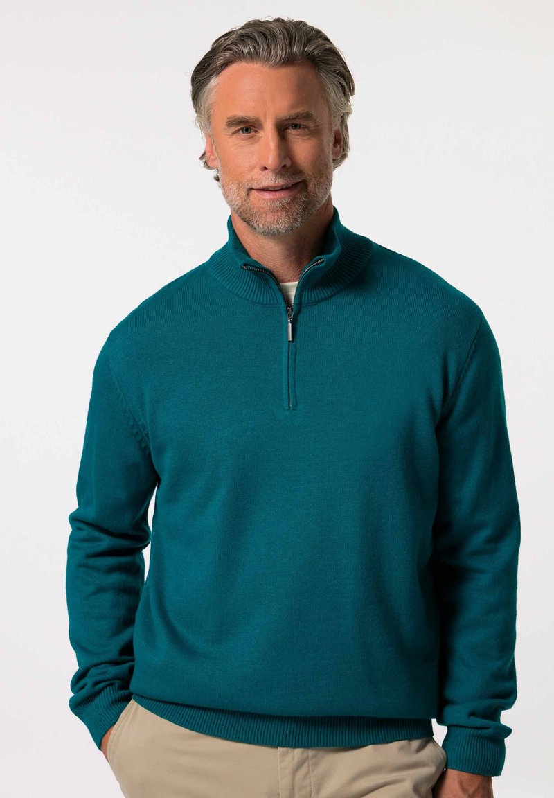 Teal slipover-tröja med hög krage och dragkedja, tillverkad av strukturerat stickat material. Ribbad ärmslut och kant ger detalj.