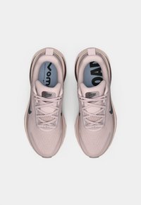 Jasnoróżowe buty sportowe z siateczkową cholewką, sznurowadłami, czarnym logo w kształcie łyżwy, wyściełaną podeszwą oraz niebieską wkładką z napisem 'RUN'.