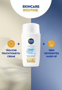NIVEA Sun Invisible Daily UV Fluid in einer weißen Flasche, mit einem blauen Etikett mit goldenen Akzenten und SPF 50+, vor einem hellen Hintergrund.