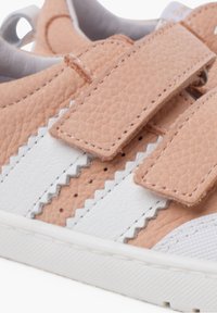 Sneaker rosa con texture e dettagli bianchi, caratterizzate da due strap in velcro e un motivo a zigzag sui lati. Suola in gomma con perforazioni.