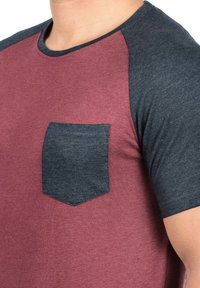 Men's T-shirt featuring maroon body with dark gray raglan sleeves and a dark gray chest pocket; made from soft cotton blend fabric.