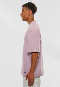 Lyslilla kortærmet t-shirt med en afslappet pasform, lavet af blød bomuld, med et minimalistisk logo-tag på kanten.