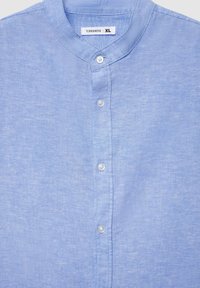 Camicia azzurro chiaro a maniche corte in tessuto morbido, con colletto alla coreana e chiusura frontale con bottoni bianchi. Taglia XL.