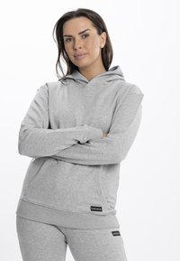 Felpa grigia realizzata in un morbido tessuto testurizzato, con una tasca frontale, polsini a costine e un cappuccio. Presenta dettagli del logo sull'orlo.