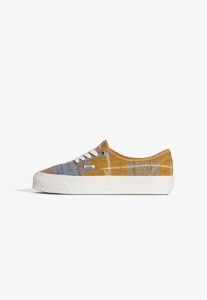 Sneakers in tela a scacchi giallo con accenti blu, suola in gomma bianca e lacci bianchi a contrasto. Presentano un'etichetta con marchio sul lato.