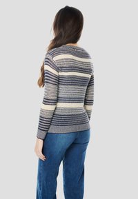 Pleteni pulover z mornarsko modrimi in kremnimi vodoravnimi črtami, z okroglim izrezom in dolgimi rokavi. Mehka tekstura, prilegan v pasu in z rebrastim robom.