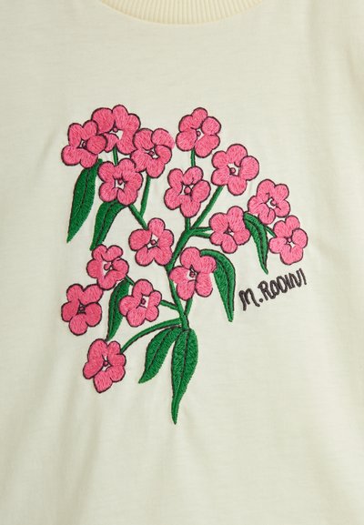 Šviesiai kreminė džemperis su ryškiais rožiniais gėlėmis ir žaliosiomis lapėmis. Jame taip pat yra juodu siūlu išsiuvinėtas logotipas "M. Rodini."
