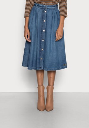 Jupe midi en denim bleu à boutons sur le devant, portée avec un top marron rayé à manches longues et des bottines beige.