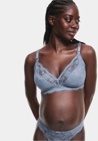 Un reggiseno in pizzo azzurro chiaro e un perizoma abbinato presentano motivi floreali, bordi ondulati e spalline regolabili. Texture liscia e design delicato.
