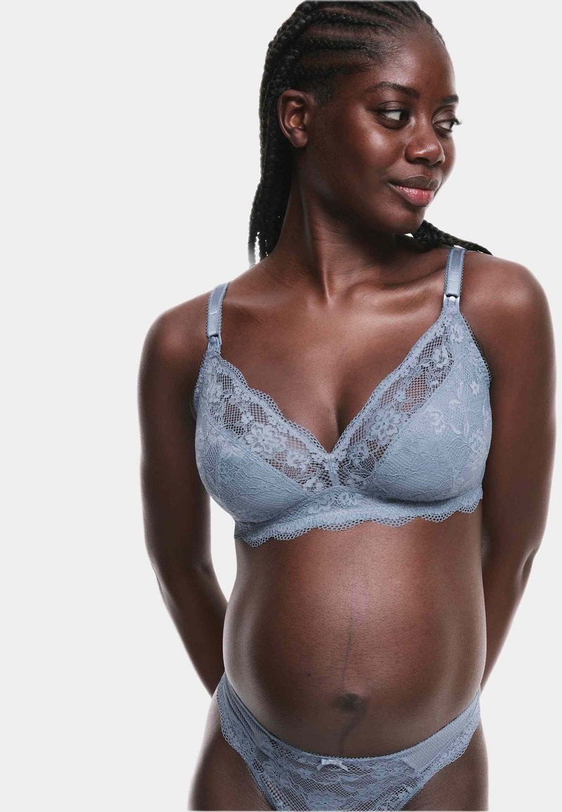 Un reggiseno in pizzo azzurro chiaro e un perizoma abbinato presentano motivi floreali, bordi ondulati e spalline regolabili. Texture liscia e design delicato.