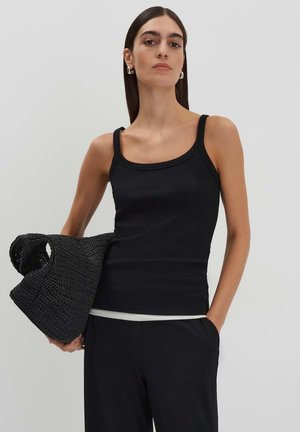 Black ribbed tank top with thin straps, paired with a textured black woven bag. The top features a fitted design and smooth fabric.