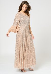 Robe longue asymétrique en pêche avec des embellissements en argent. Présente des détails de manches volantes et une jupe plissée légère.