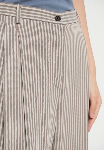 Beżowo-białe, w pionowe paski spodnie z płaskim przodem, kieszeniami bocznymi i brązowym zapięciem na guzik. Materiał wydaje się być tkany i ma gładką teksturę.