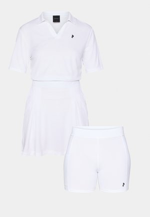 Un outfit sportiv alb, inclusiv un polo cu mânecă scurtă și decolteu în V cu logo, combinat cu o fustă plisată și pantaloni scurți mulați.