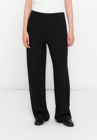 Zwarte wijde broek met een soepele textuur, voorzien van een middelhoge taille, twee zijzakken en een strakke, minimalistische uitstraling.