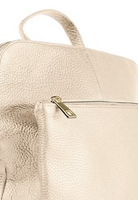 Beige leren rugzak met een gestructureerde afwerking, voorzien van een gouden ritsluiter en een handvat aan de bovenkant. Voorkant met een zichtbare ritszak.