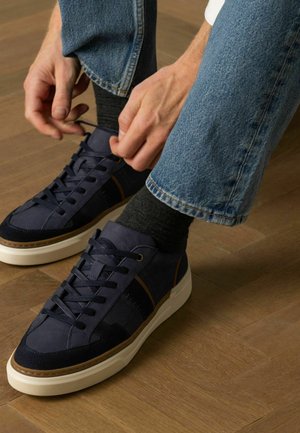 Marine sneakers gemaakt van leer en suède met een witte zool, voorzien van tonale veters, textuurpanelen en bruine accenten.