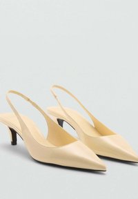 Béžové kožené sandále na opätku s ostrou špičkou a nízkym čiernym opätkom. Hladká textura a minimalistický dizajn s otvorenou zadnou časťou.