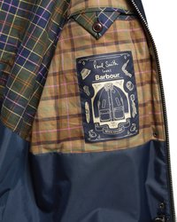 Вътрешна страна на сако от плат с каре с пришит етикет, на който пише "Paul Smith loves Barbour", и изображение на сако и аксесоари.