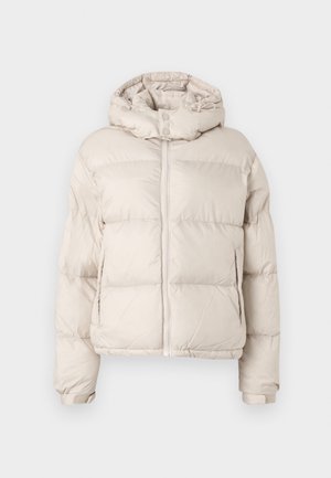 Puffermantel in hellbeige mit hohem Kragen und Reißverschluss vorne, versehen mit Druckknöpfen. Er hat ein gestepptes Design und elastische Bündchen.