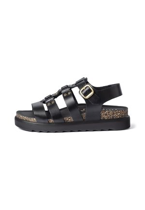 Black leather sandal with adjustable gold buckle, cork footbed, thick black sole, and multiple straps across the foot and ankle.