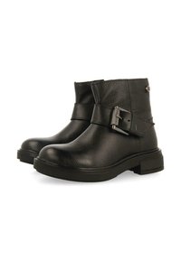 Botas de tobillo de cuero negro con un acabado texturizado, que cuentan con una correa lateral y detalle de hebilla, puntera redonda y tacón de goma bajo.