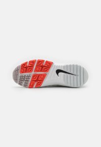 Baltas sporta apavu zole ar melnu Nike logotipu, sarkaniem saķeres spilventiņiem un teksturētu gumiju dažādās rakstu formās, lai nodrošinātu saķeri.