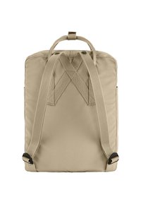 Sac à dos beige en tissu rembourré, avec des bretelles croisées, deux poches latérales et des coutures renforcées. Bretelles réglables et profilées.