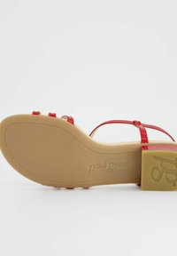 Czerwone sandały z lakierowanej skóry z cienkimi paskami i słupkowym obcasem. Teksturowana beżowa podeszwa z wytłoczonym logo marki. Gładkie wykończenie, nowoczesny design.