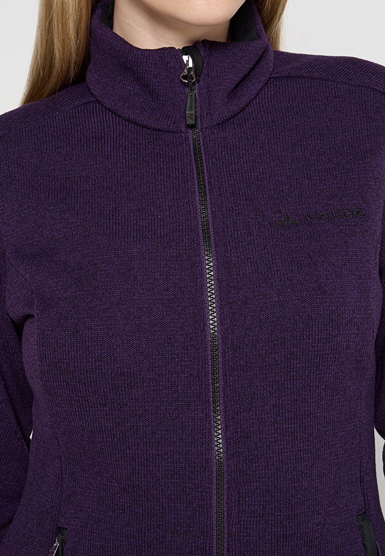 Lila Fleecejacke mit hohem Kragen, vollem Reißverschluss vorne und schwarzen Akzenten. Verfügt über einen strukturierten Stoff und dezente Markenkennzeichnung auf der Brust.