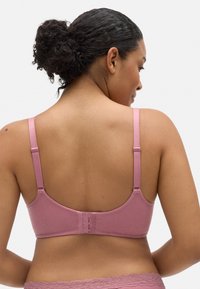 Sostén rosa con relieve, con tirantes ajustables y cierre de gancho y ojo en la parte posterior. La textura suave y el diseño sin costuras brindan comodidad y soporte.